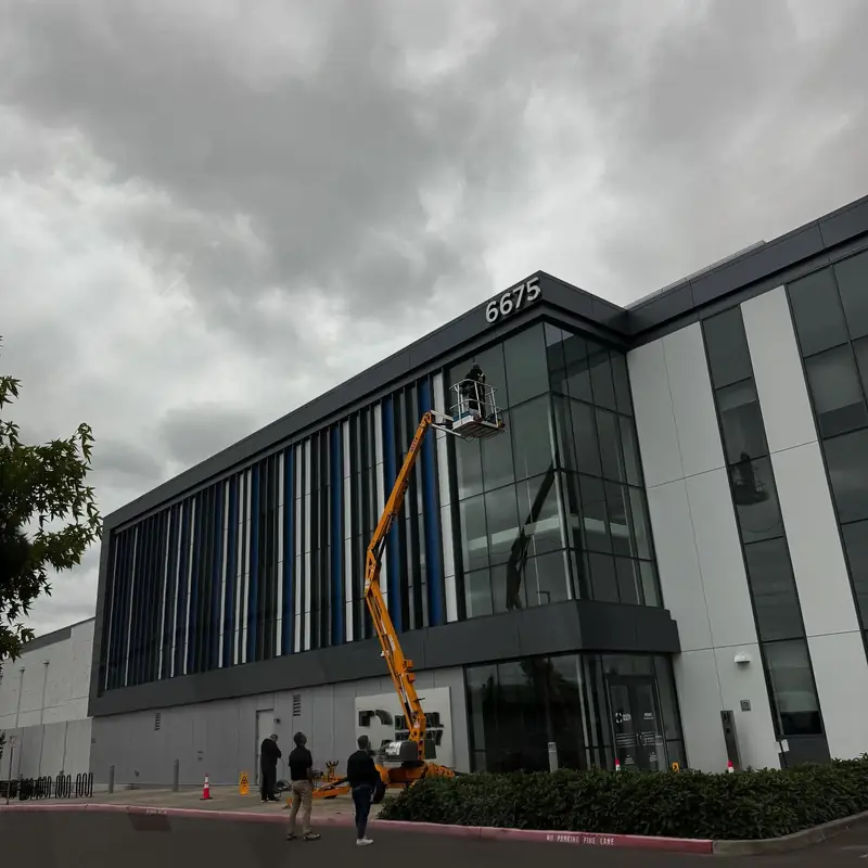 Corporate Cleaning Service technician on a boom lift cleaning high windows on a large commercial building